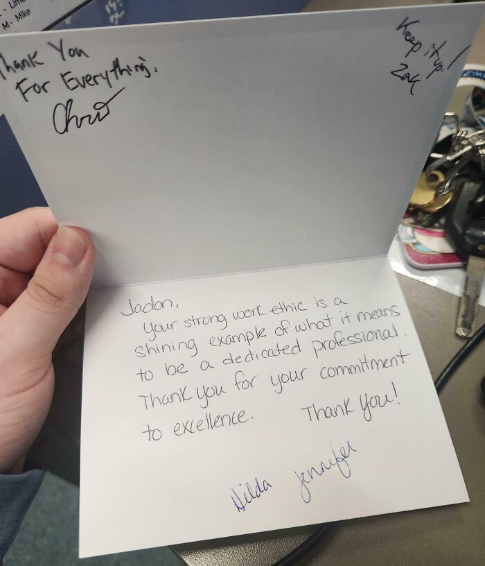 Hand holding a signed thank-you card from bosses, praising strong work ethic.