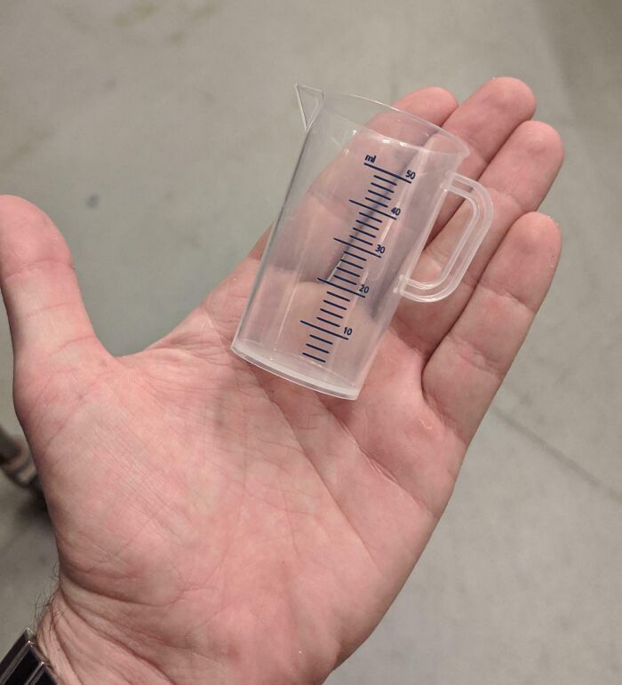 Tiny measuring cup held in a palm, showcasing Good-Funny-Bosses humor.