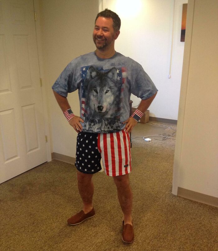 Man in wolf shirt and American flag shorts, embodying good funny bosses with a cheerful pose.