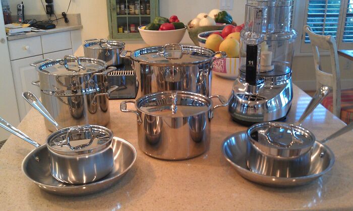 Shiny kitchen pots and pans on a countertop next to a blender.