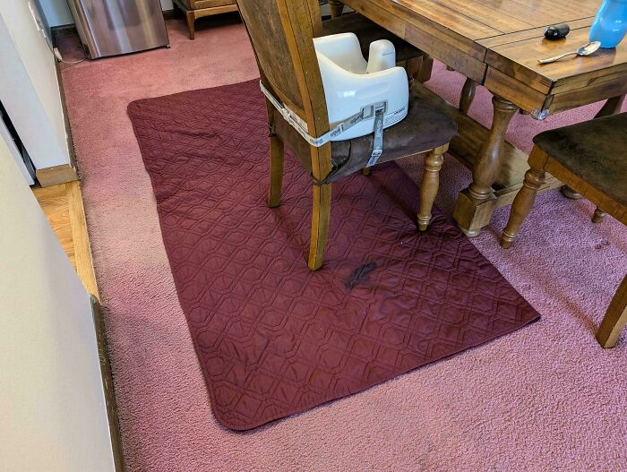 Dining chair with toddler booster seat on a spill-proof mat, showcasing parenting genius tricks for easy cleanup.