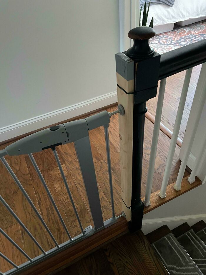 Child-safe gate installed at top of wooden staircase, showcasing parenting tricks for home safety.