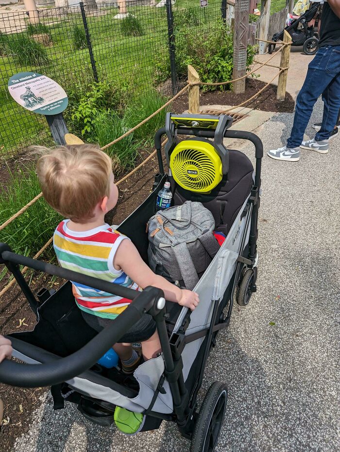 A child in a stroller with a portable fan attached, showcasing parenting-genius-tricks for comfort on a sunny day.