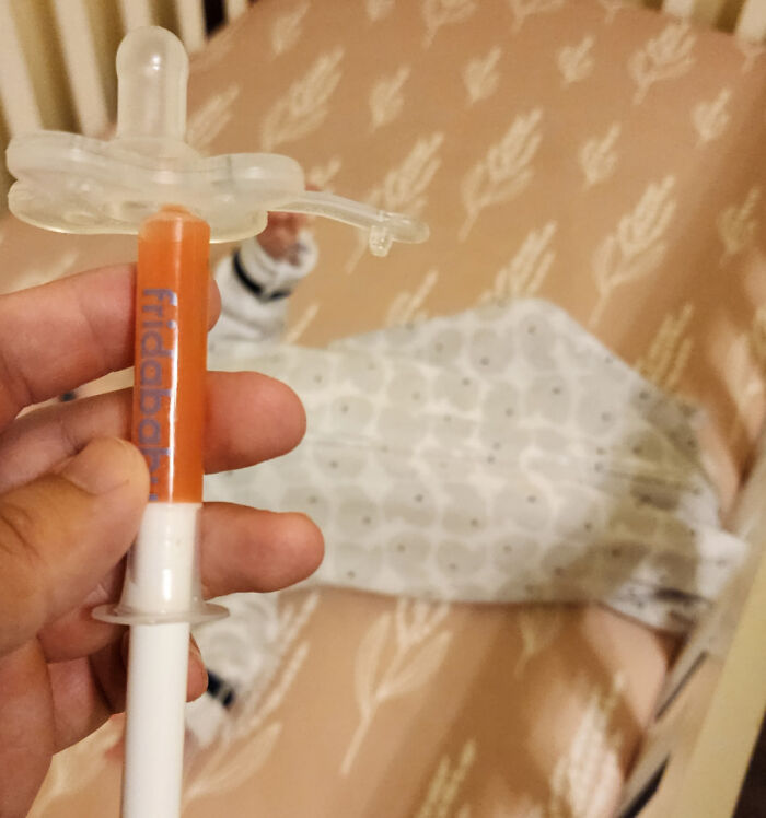 Parenting genius trick: modified pacifier syringe held in front of baby in crib, for easy medicine administration.