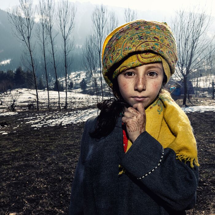 Young girl wearing a colorful headscarf in a snowy landscape, captured by Hamed AlGhanboosi.