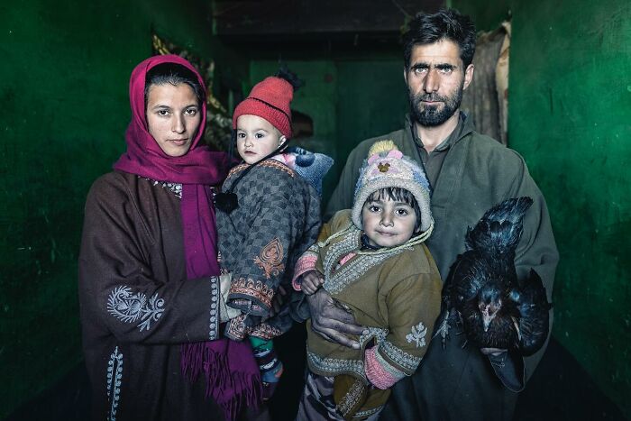 Family portrait by Hamed AlGhanboosi, featuring parents, two children, and a chicken, set against a green background.