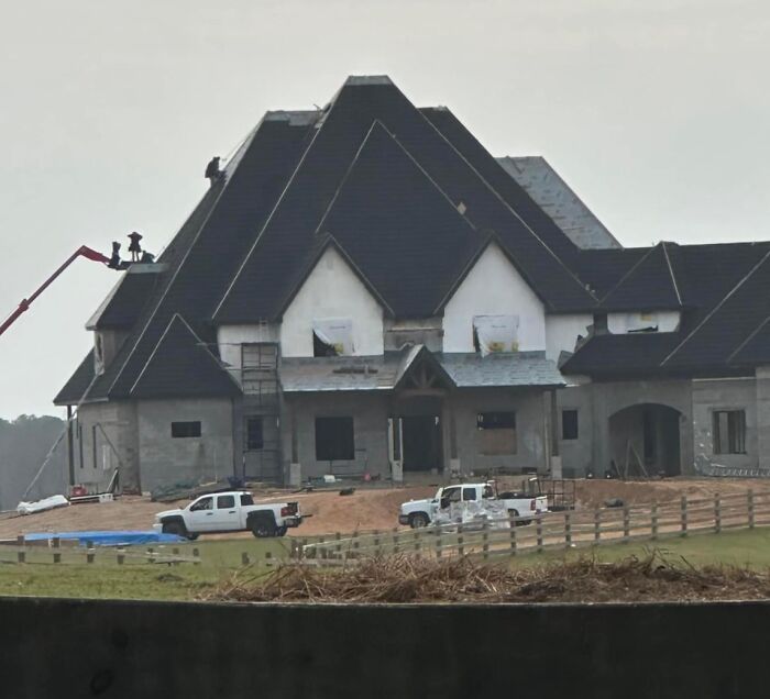 Large, unfinished mansion in a rural setting, showcasing poor architectural taste despite evident wealth.