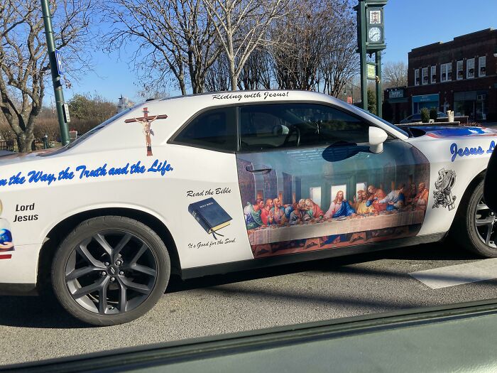 Car-fails: Car with religious imagery and Last Supper decal parked on the street.