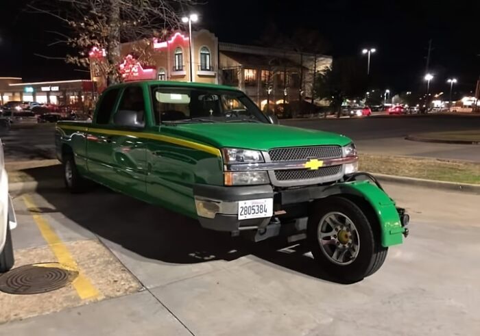 Green truck with missing front wheels, illustrating a car-fails moment in a parking lot at night.