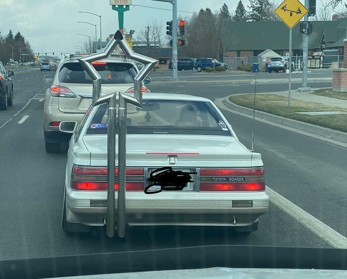 Modified car on the road with a tall star-shaped exhaust, illustrating a humorous car-fail moment.