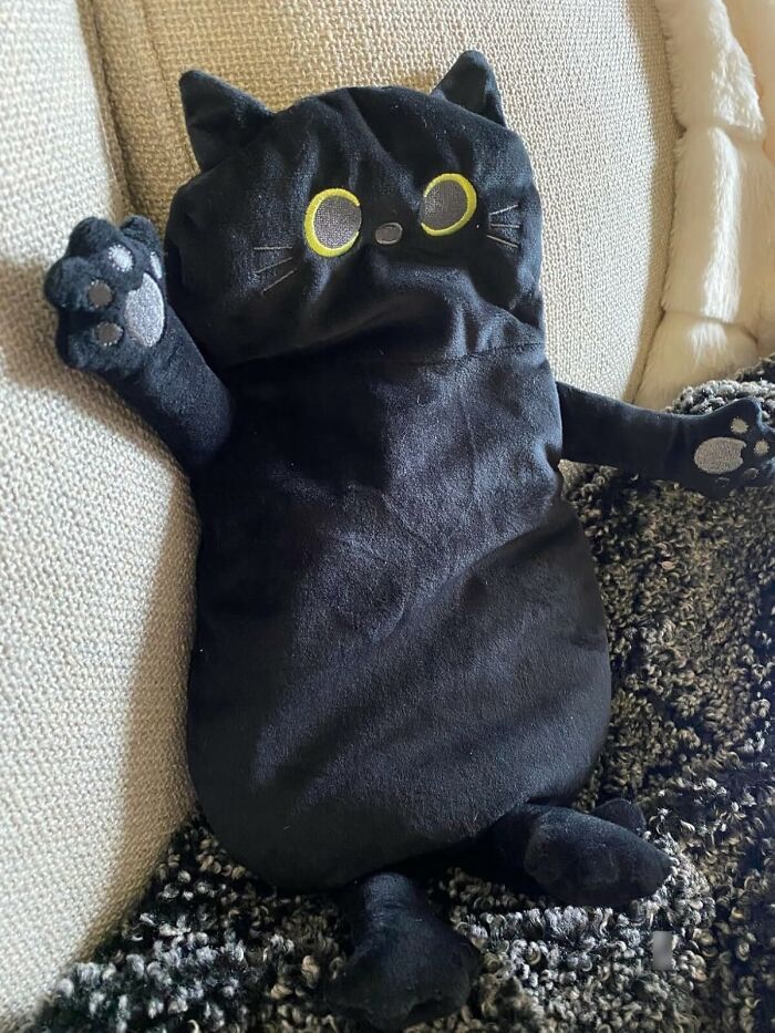 Plush black cat pillow on a couch, perfect unique gift for women for Christmas.