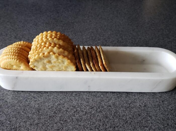 Marble cracker holder, a unique gift for women, on a gray countertop.