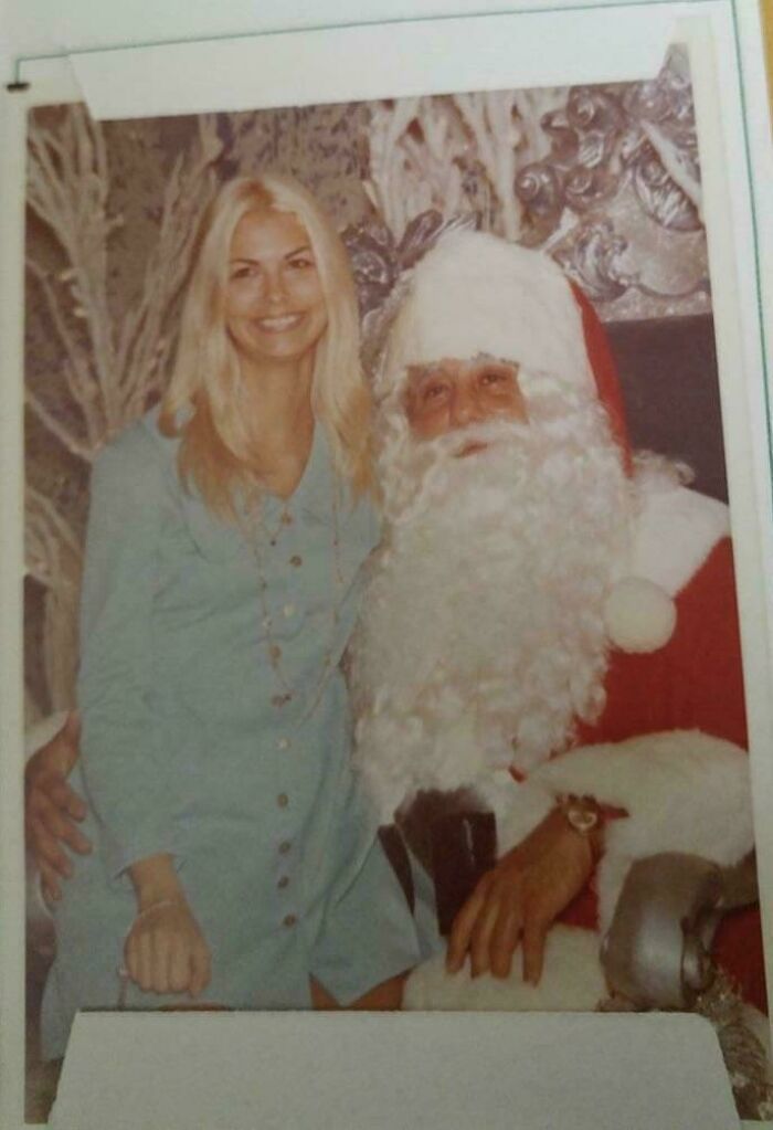 A woman in a 60s fashion outfit poses with Santa Claus, showcasing vintage style.