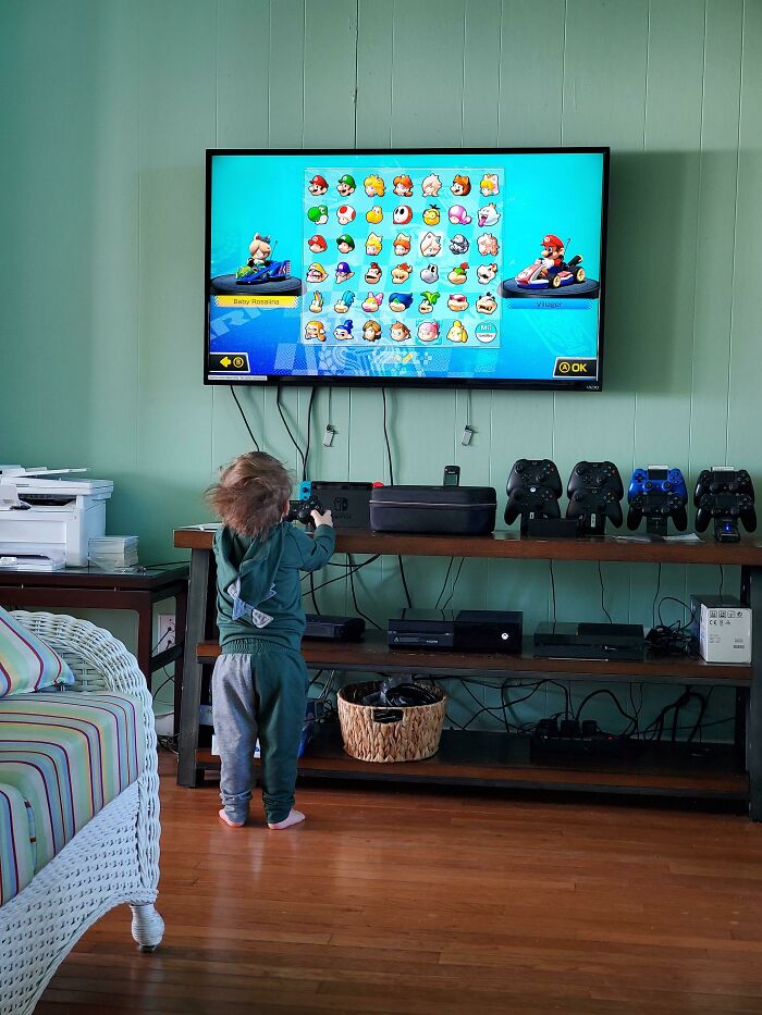 Toddler playing a video game, creatively engaging with a television screen, highlighting Parenting-Genius-Tricks.