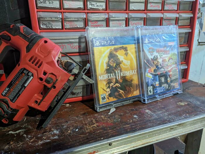 A jigsaw cutting into a PS4 game case, placed on a workbench, illustrating Christmas accidents gone wrong.