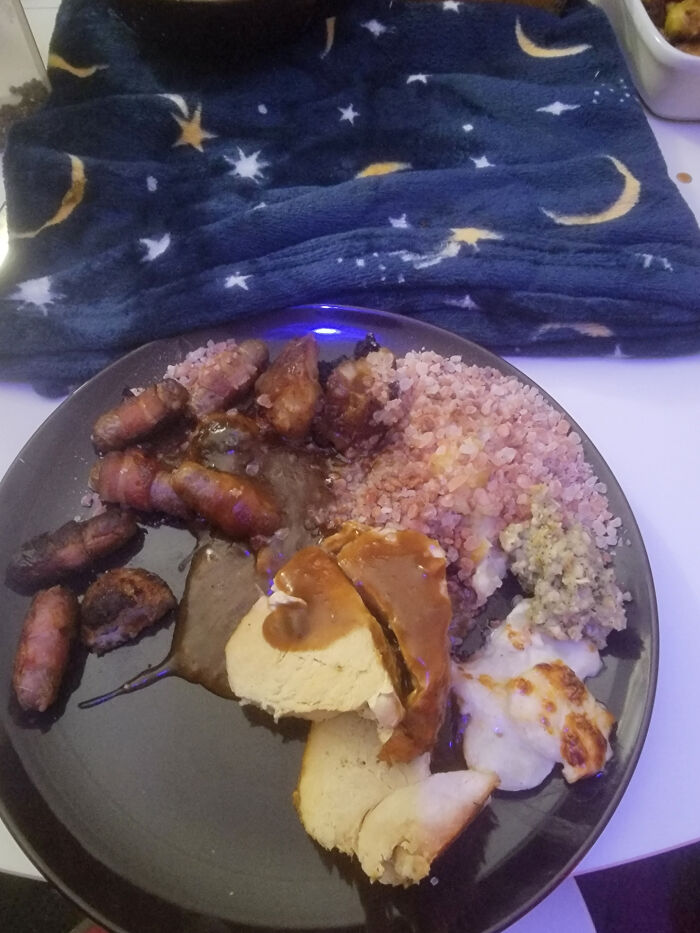 Plate with charred sausages, turkey slices, gravy, and stuffing, suggesting a Christmas cooking mishap or accident.