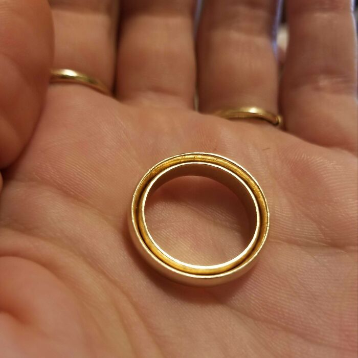 A gold ring fitting snugly inside another ring in a person's palm, showcasing a satisfying perfect fit.