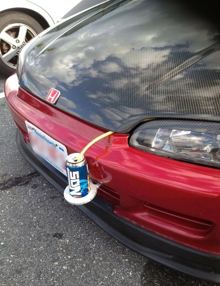 Red car with a DIY front end using a soda can and plastic plate, representing car-fails creativity.