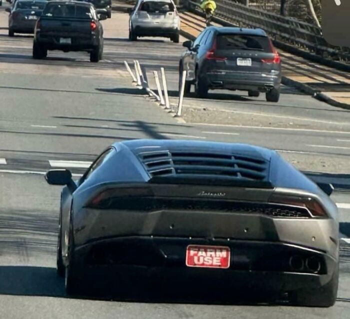 Luxury car with "Farm Use" tag on the road, surrounded by traffic.