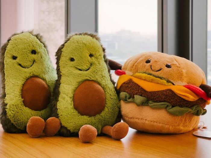 Plush avocado and burger toys on a wooden table, perfect gifts for teens.