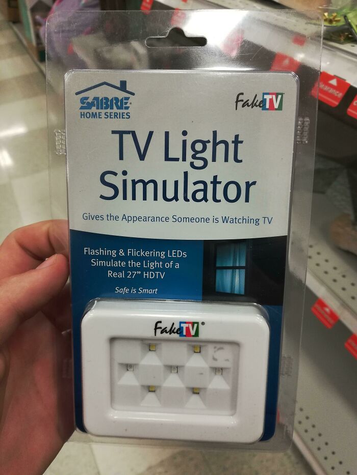 Fake TV light simulator package, creating illusion of TV light with LEDs, held in hand at store aisle.