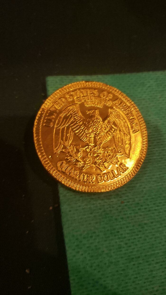 Gold chocolate coin placed on a green and black surface, symbolizing Christmas mishaps.