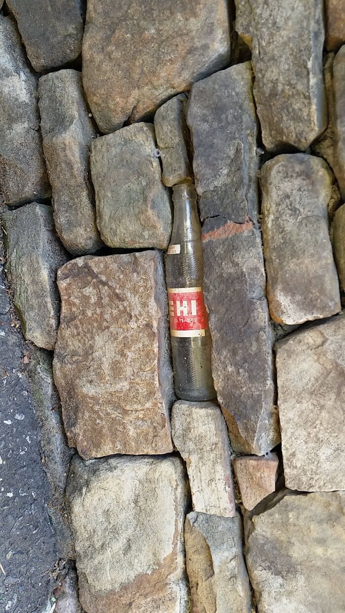 Bottle perfectly fitting into stone wall gap, illustrating satisfying perfect fit.