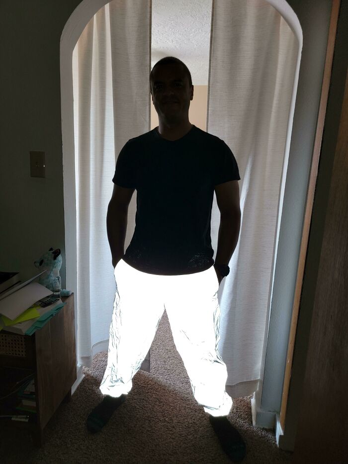 Man standing with glowing pants in a dimly lit room, creating a fascinating visual effect.