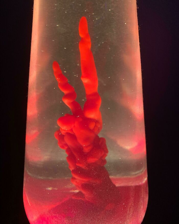 Red lava lamp wax forming unique shapes inside a glass container, glowing with a warm light.