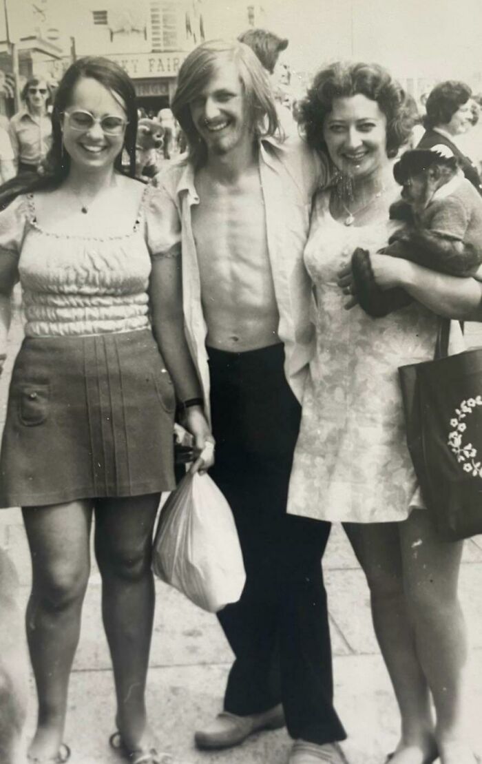 Three people in 60s fashion, with a woman holding a monkey, capturing the retro style of the era.