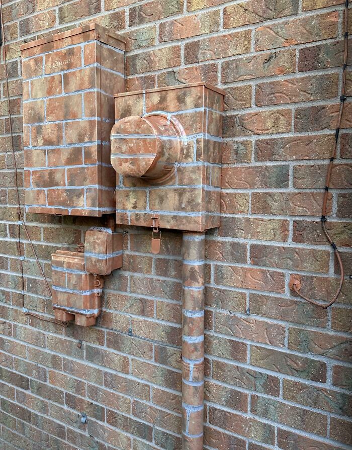 Camouflaged utility boxes on a brick wall, blending seamlessly with the pattern. Fascinating picture highlighting clever design.