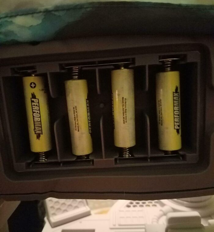 Four batteries in a battery compartment, showcasing a parenting genius trick for organizing and managing batteries effectively.