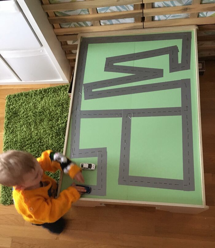 Child playing with toy cars on a homemade road map, showcasing a parenting genius trick for creative play.