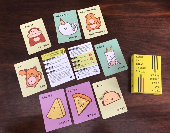 Fun animal and food cards from the Taco Cat Goat Cheese Pizza game laid out on a wooden table.