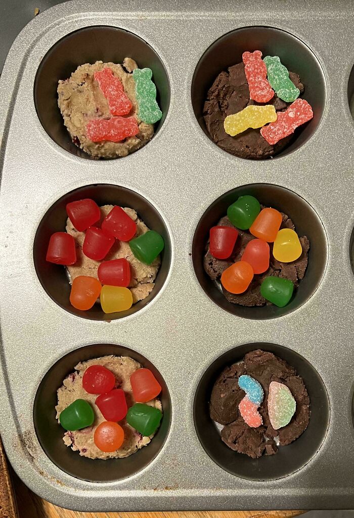 Muffin tray filled with accidental cookies topped with colorful candy for Christmas.