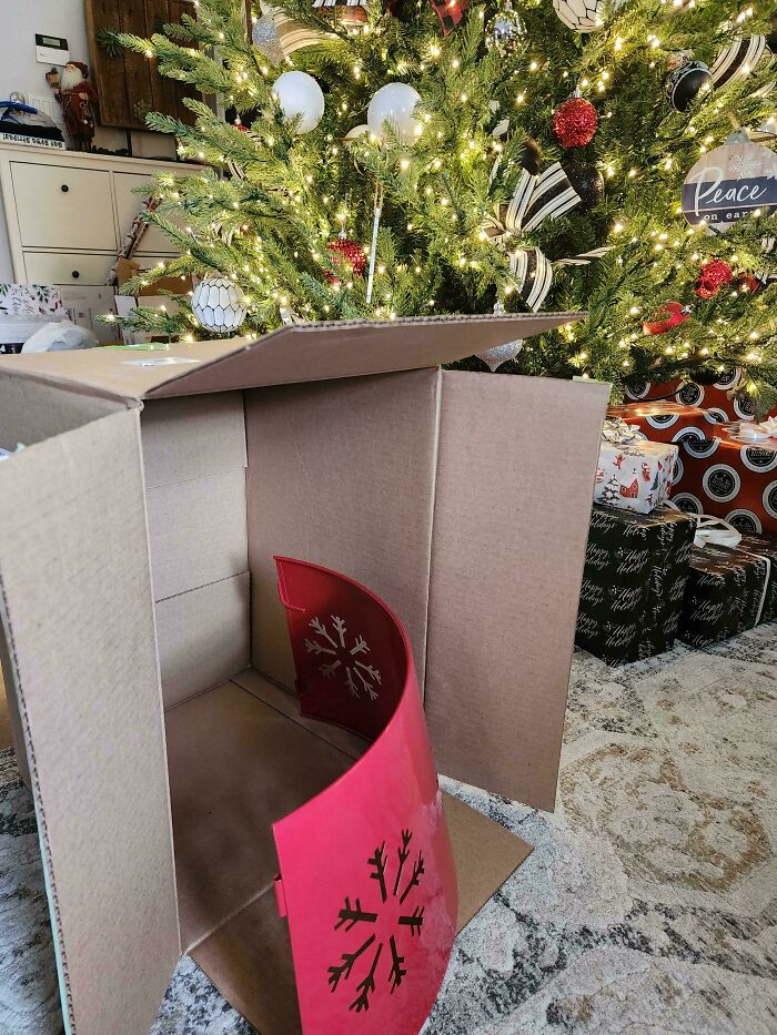 Christmas accident with an empty box and broken decoration near a lit tree.