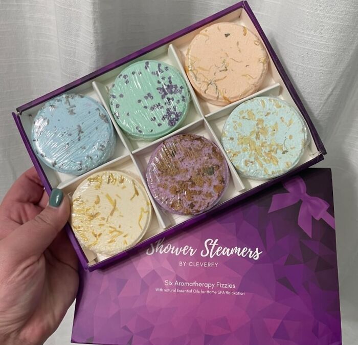 Colorful shower steamers set, great gifts for your mom, held in hand, featuring six aromatherapy fizzies in a purple box.