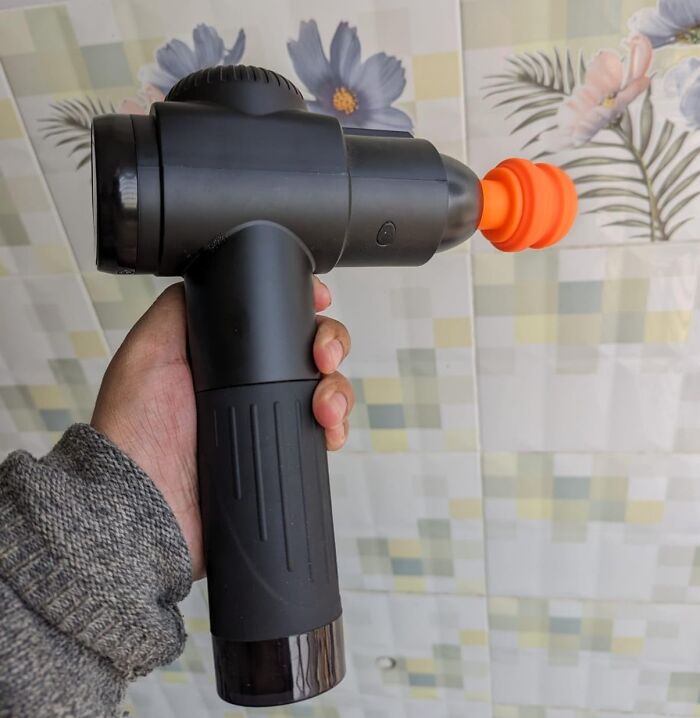 Hand holding a black massage gun, an ideal gift for your mom.