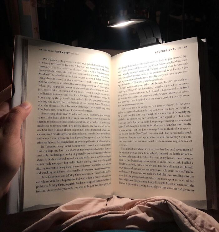 A person reading a book under a small lamp, ideal gift ideas for your mom who loves reading.