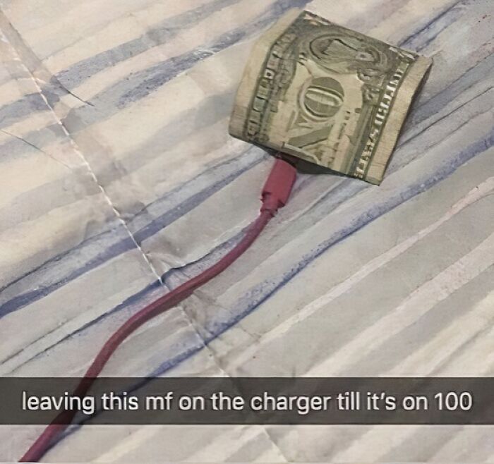 Dollar bill humorously wrapped around a phone charger on a bed, illustrating an unhinged moment.