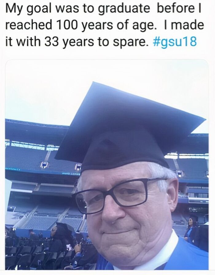 Elderly man in graduation cap and gown, smiling proudly in a stadium setting, representing wholesome achievement.