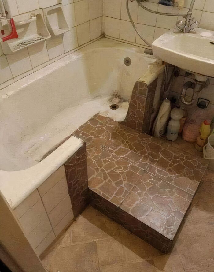 A humorous construction fail with a bathtub blocked by a tiled step, making it unusable.