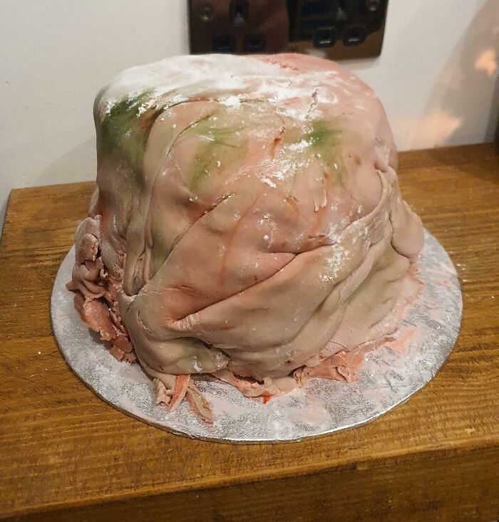 Unsuccessful Christmas cake with uneven icing on a wooden table, illustrating a baking mishap.