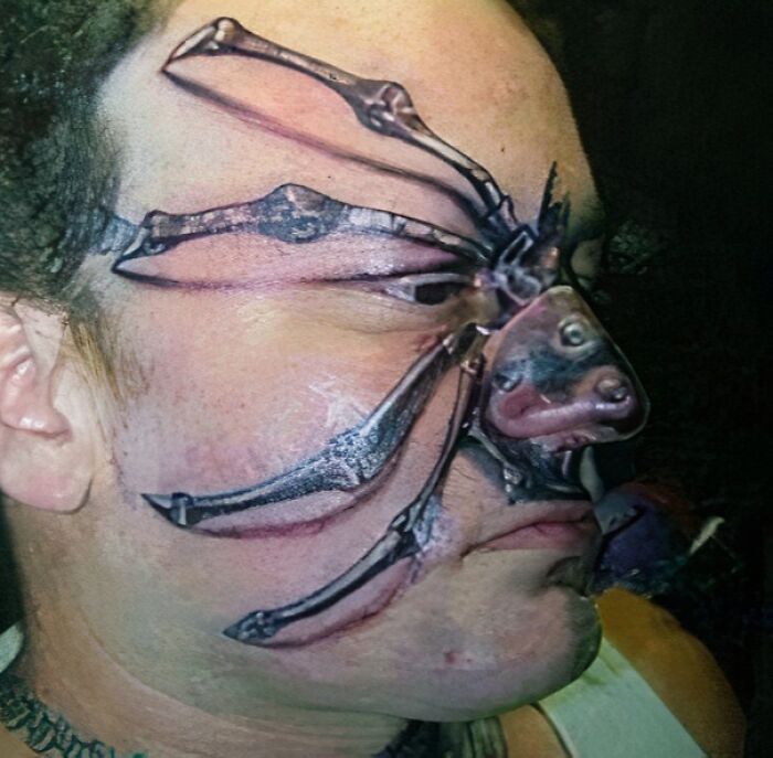 A man with an epic tattoo fail resembling a spider on his face, showing bold and detailed ink work.