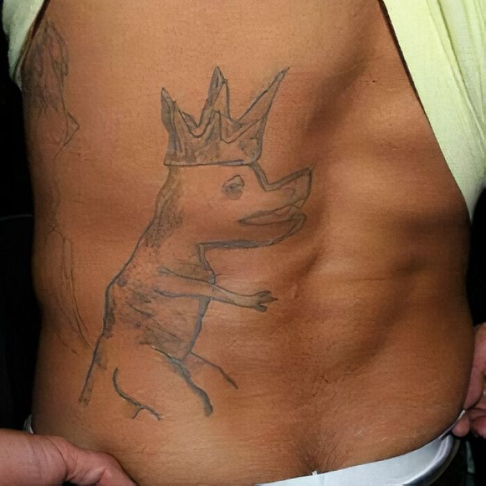 Epic tattoo fail of a poorly drawn crowned animal on a person's side.