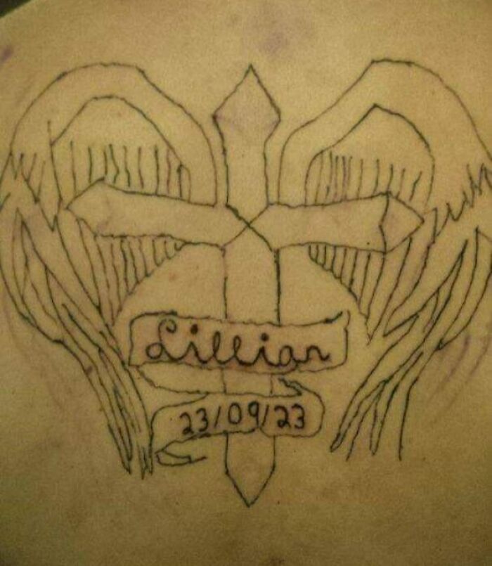 Back tattoo depicting a cross with wings and text, representing an epic tattoo fail.