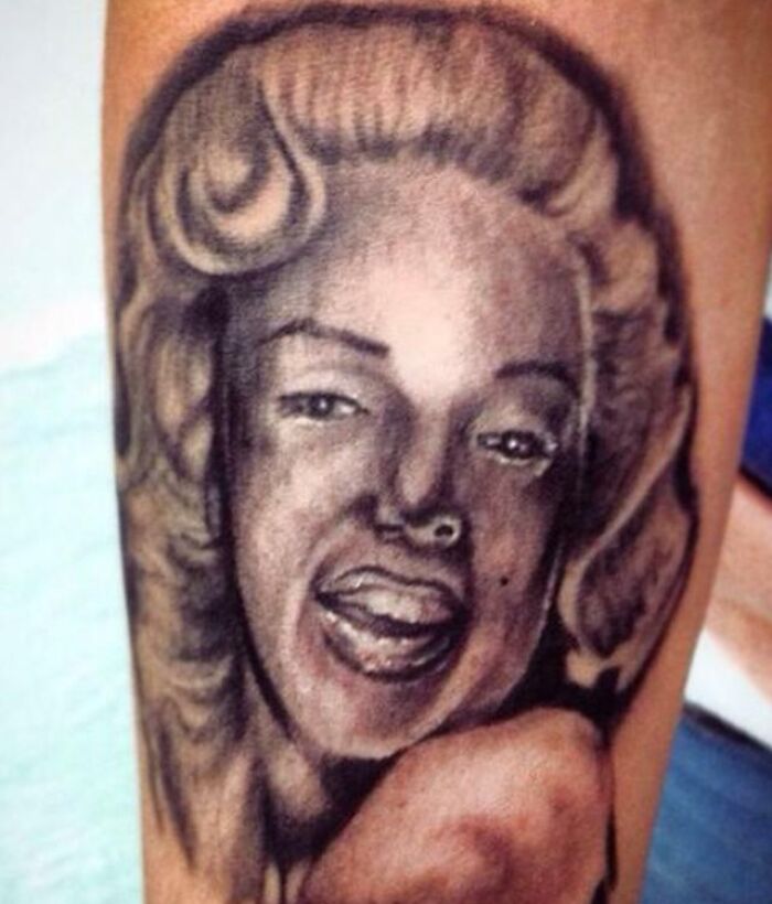 Epic tattoo fail depicting a poorly drawn portrait on a person's arm.