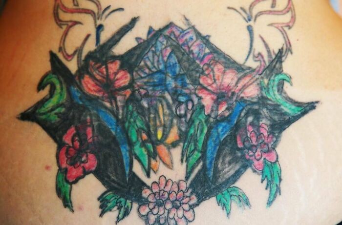 Poorly executed tattoo with colorful flowers and abstract shapes highlighting tattoo fails.