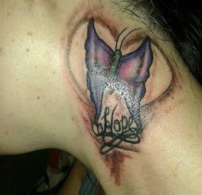 Close-up of an epic tattoo fail featuring a butterfly with the word "hope" on a person's neck.