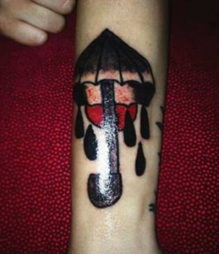 Epic tattoo fail featuring a poorly drawn umbrella with black ink drips on an arm.